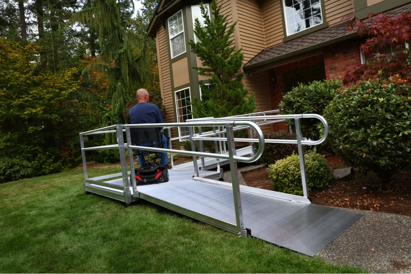 A man rides his power chair up a Lifeway Mobility ramp in order to easily access the front door of his home