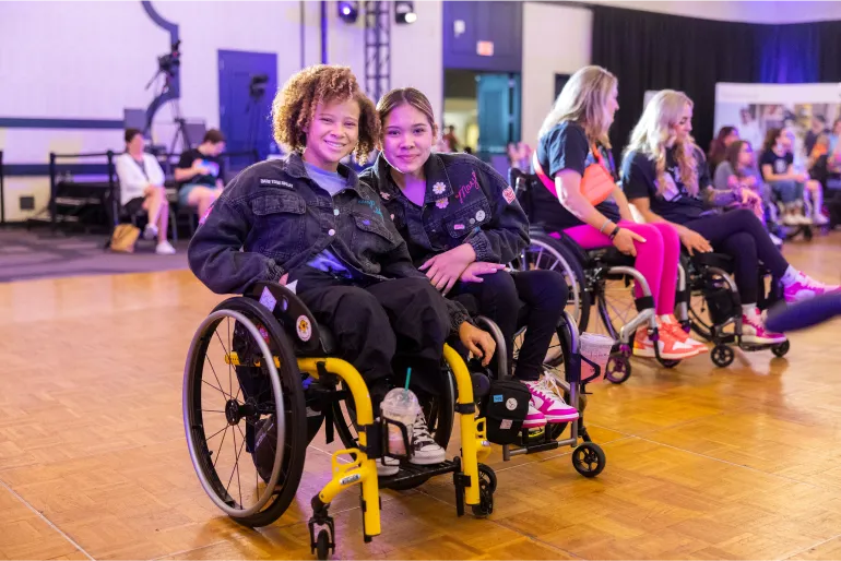 A couple of teenaged Rollettes Experience attendees pause on the dance floor to smile for the camera.