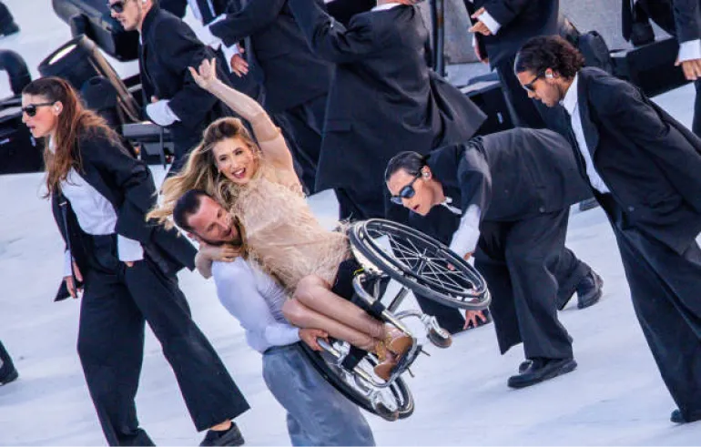 A dancer picks up Chelsie Hill in her wheelchair during a Paralympic Opening Ceremony Dance Performance.