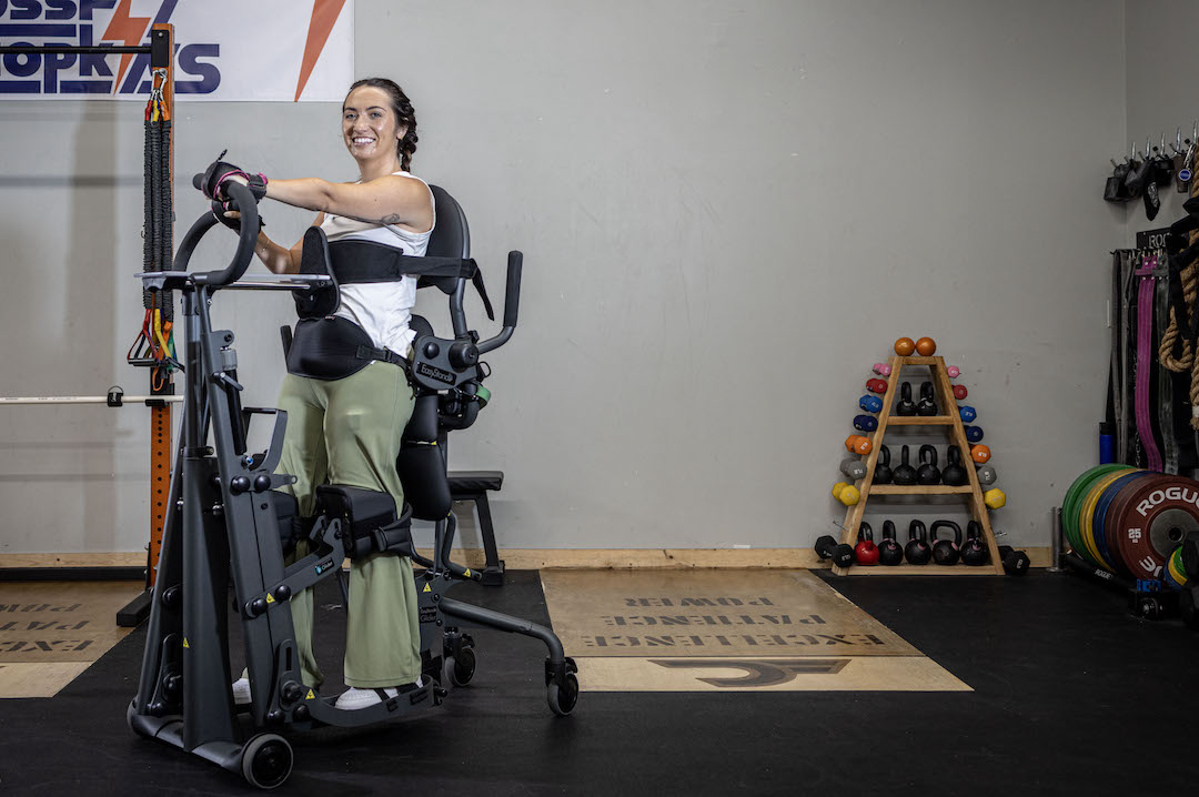 A smiling woman is fully upright and getting a great workout in her EasyStand Glider.