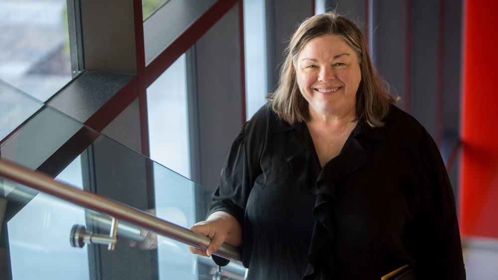 A professional headshot of Linda, where she is smiling warmly at the camera and wearing a black blouse.