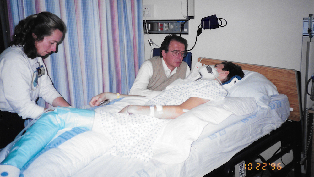 Photo of Billy Price in a hospital bed, surrounded by loved ones.