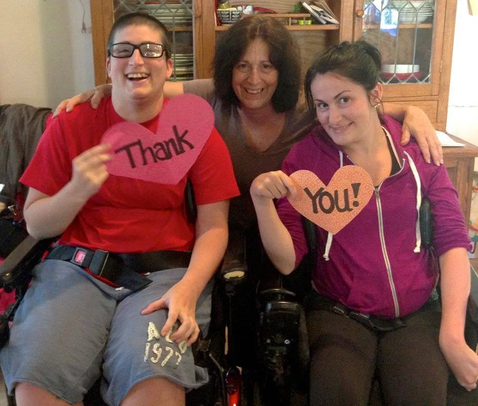 Mary Carusso and her two daughters. The girls are holding hearts that say, 