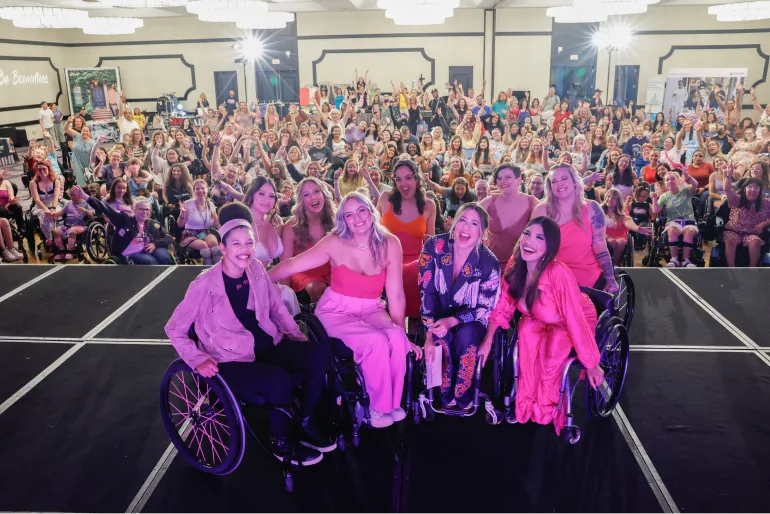 The Rollettes dance team poses on the Rollettes Experience stage with a giant crowd of RE attendees cheering behind them.