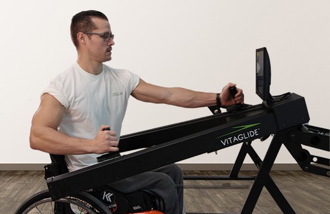 A wheelchair-user is exercising on the VitaGlide.