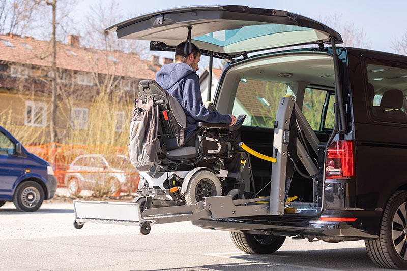 Man on a powerchair entering a van from the back on a ramp.