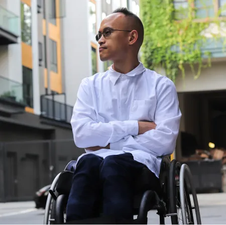 A man in a wheelchair looks great in his white, button-down adaptive shirt.