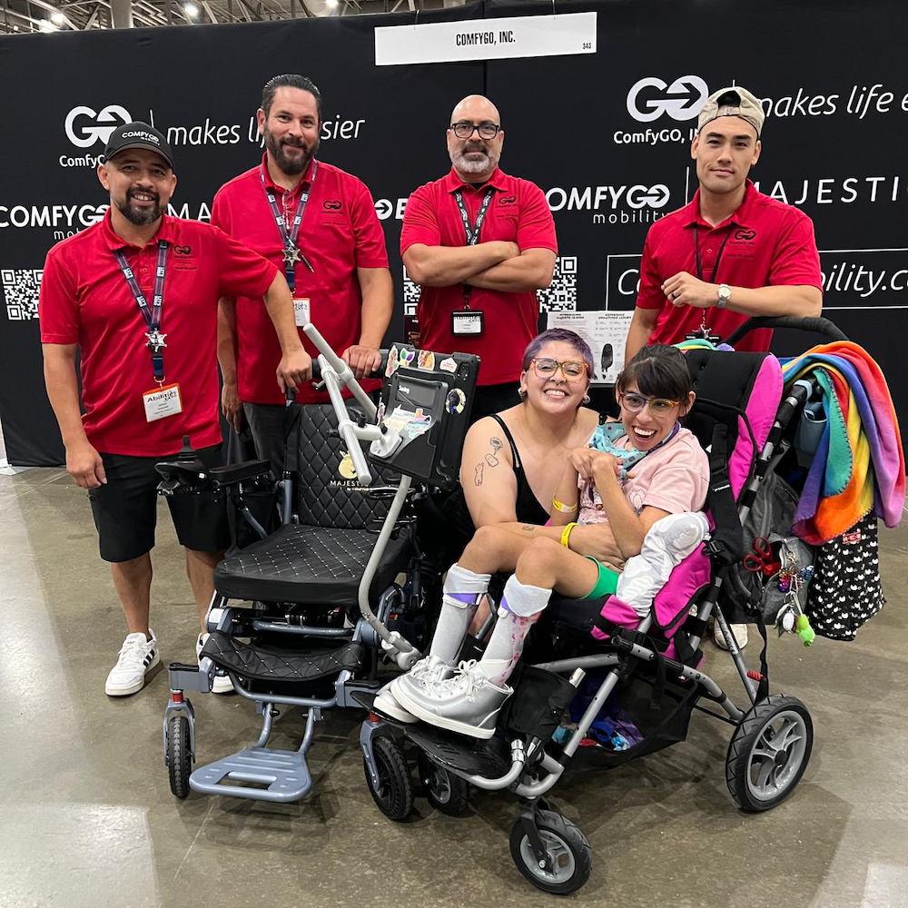 The ComfyGO crew are all smiles as they gather around a mom and her daughter with disabilities, the proud new owners of the Phoenix Carbon Fiber electric wheelchair.