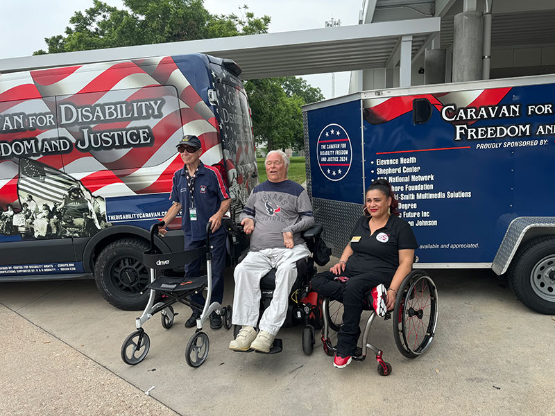  Lex Frieden, Director of the Independent Living Research Utilization (ILRU), flanked by Malcolm Brodie, his friend and assistant, and Marisa Demaya, ILRU Deputy Director, pose in front of the Caravan for Disability Freedom and Justice van at the ILRU in Houston, Texas.