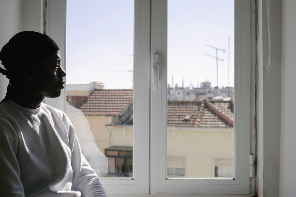 A man in a white shirt looks forlorn as he stares out the window.