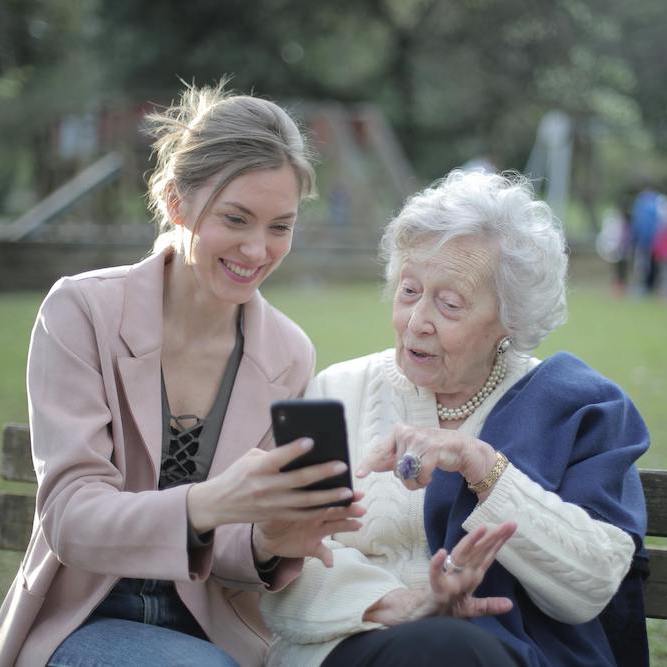 A daughter is showing her senior mother how to use a smartphone.