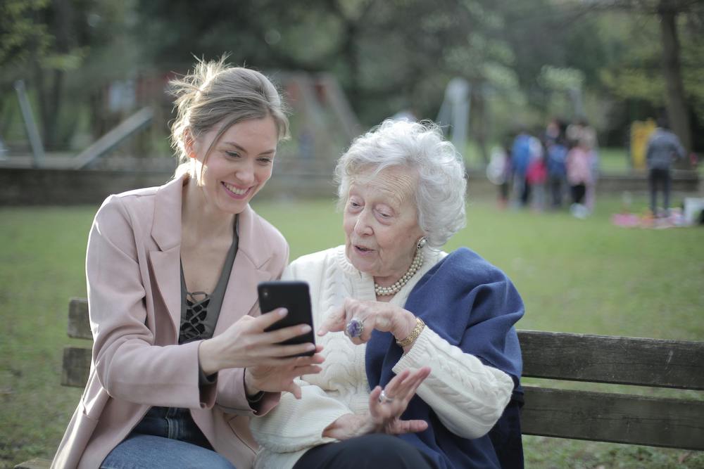 A daughter is showing her senior mother how to use a smartphone.