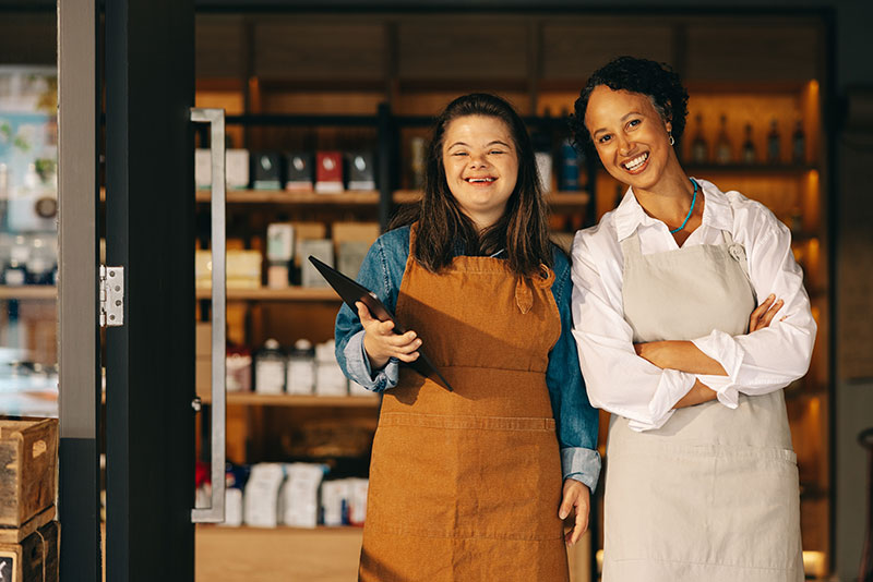 Self awareness: two women in a workplace environment smiling at the camera