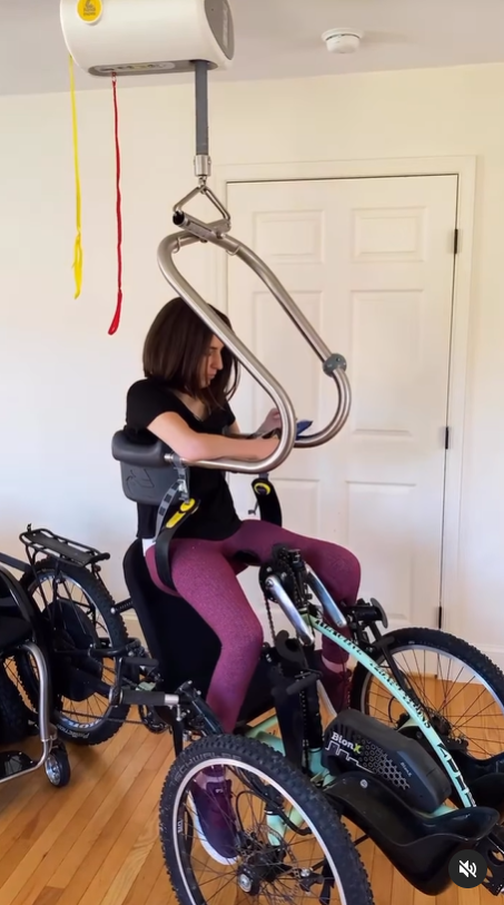 Using the SureHands lift system, a woman is lowered into her adaptive bike.