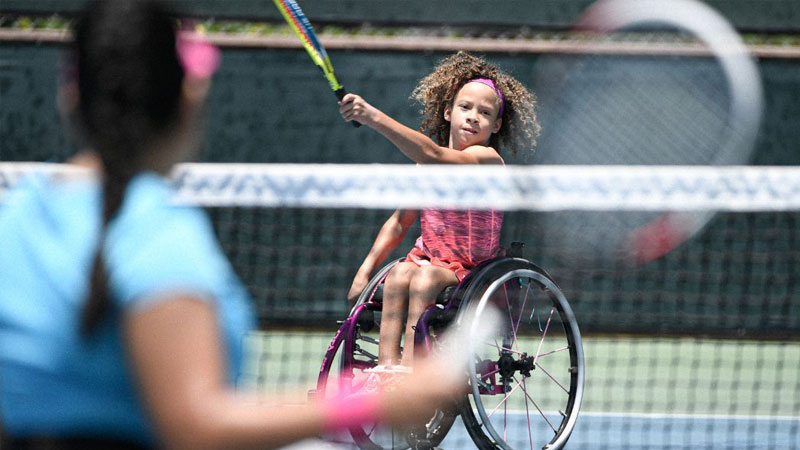 Two female wheelchair users playing tennis. 