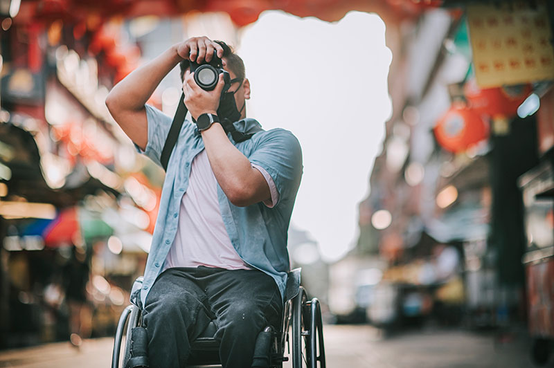 Man in wheelchair photographing an Asian city