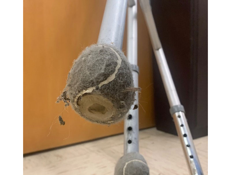 Close-up of a tennis ball walker footing which has word through and looks disgusting with its accumulation of hair and dirt.