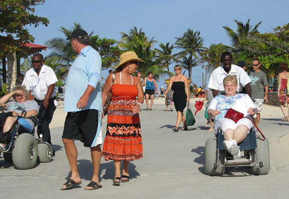 Women in wheelchairs enjoy a tropical beach day.