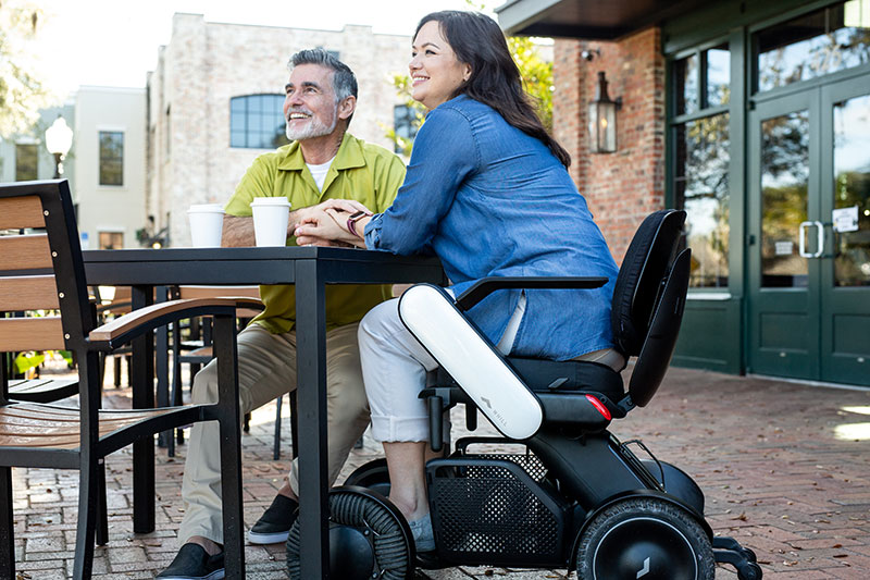 Couple outside. The female is in a Whill device.