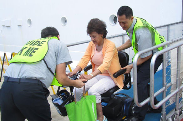 A woman is helped of a cruise ship by attentive crew.